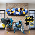 Batman-themed balloons and decorations against a brick wall.