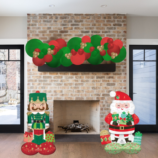 Decorative Christmas garland and figures in front of a brick fireplace.