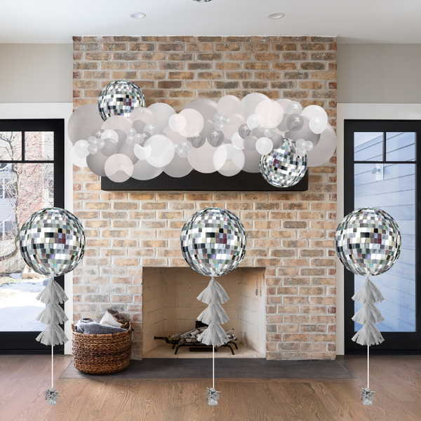 Decorative disco ball balloons in front of a brick fireplace.