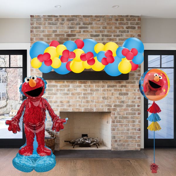 Decorative setup with Elmo balloon and figure in front of a brick fireplace.