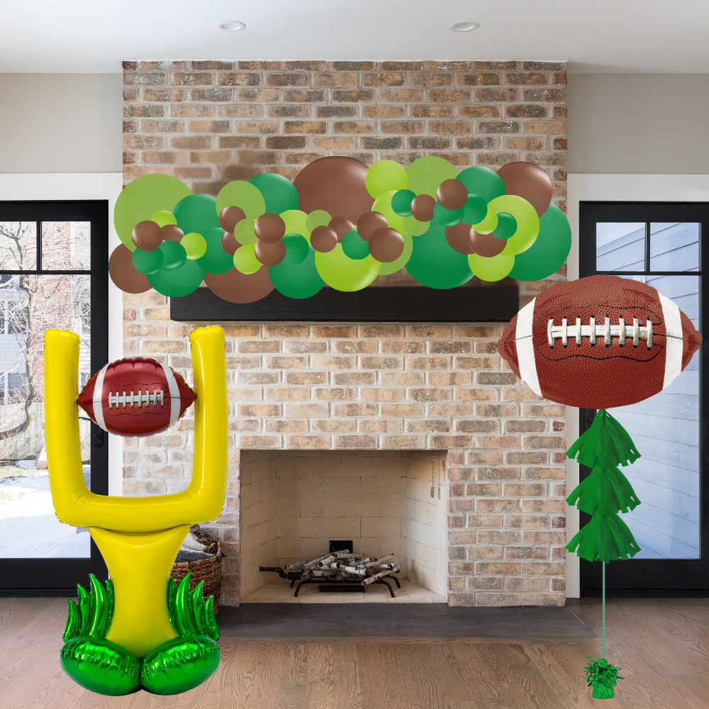 Decorative sports-themed balloons including a football, goalpost, and wreath in front of a brick fireplace.