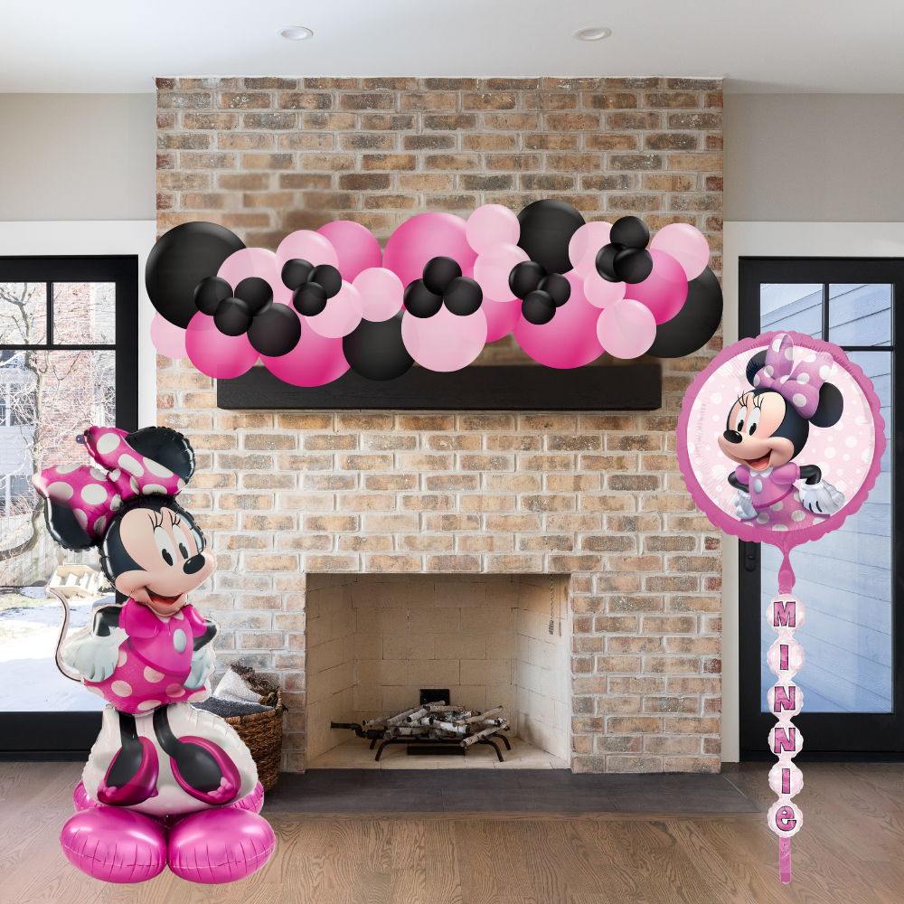 Minnie Mouse balloons and decorations in front of a brick fireplace.