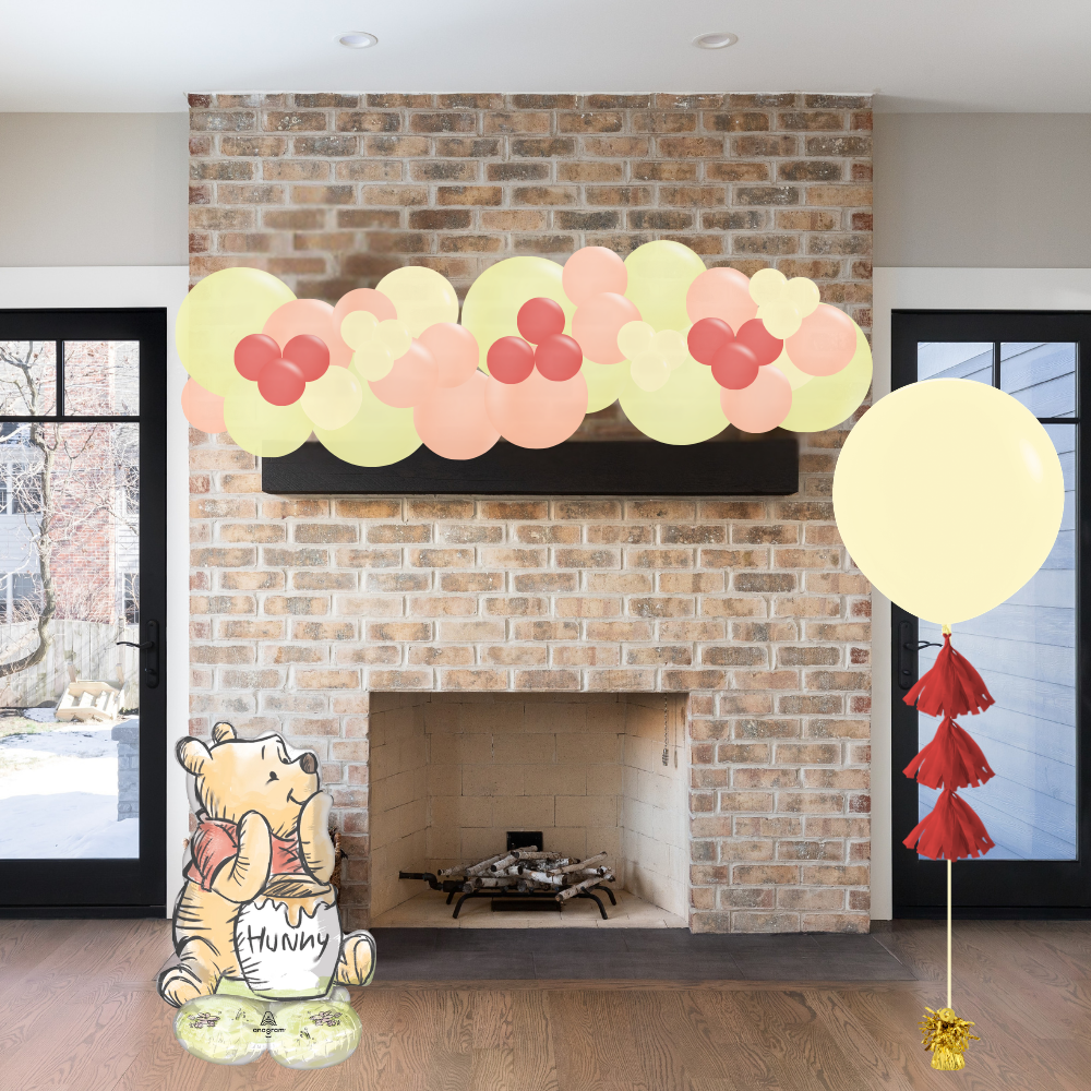 Decorative fireplace with balloons and Winnie the Pooh figure in a living room.