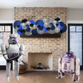 Two inflatable figures resembling a stormtrooper and R2-D2 in a living room with a brick fireplace.