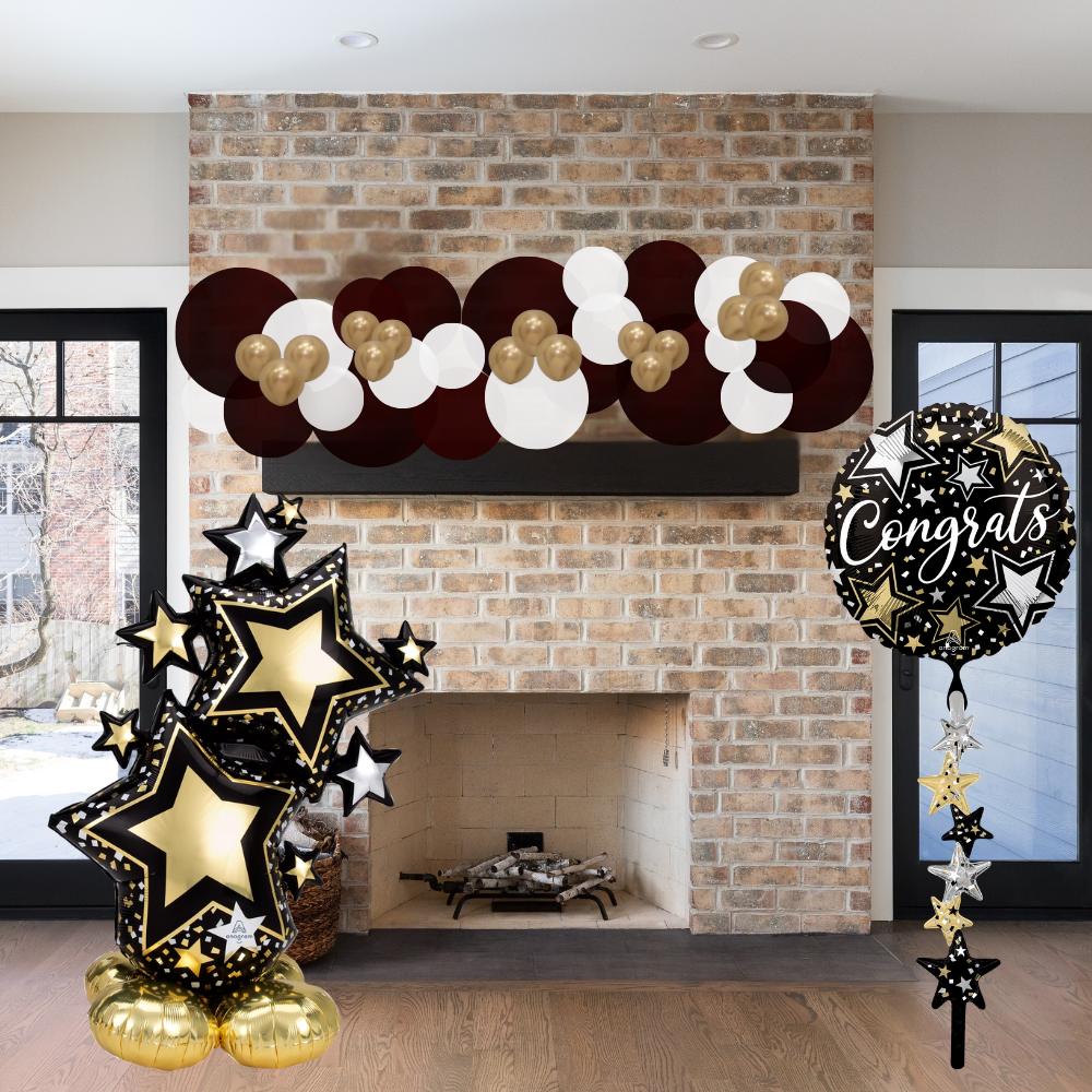 Decorative balloon arch with stars and 'Congrats' balloon in front of a brick fireplace.
